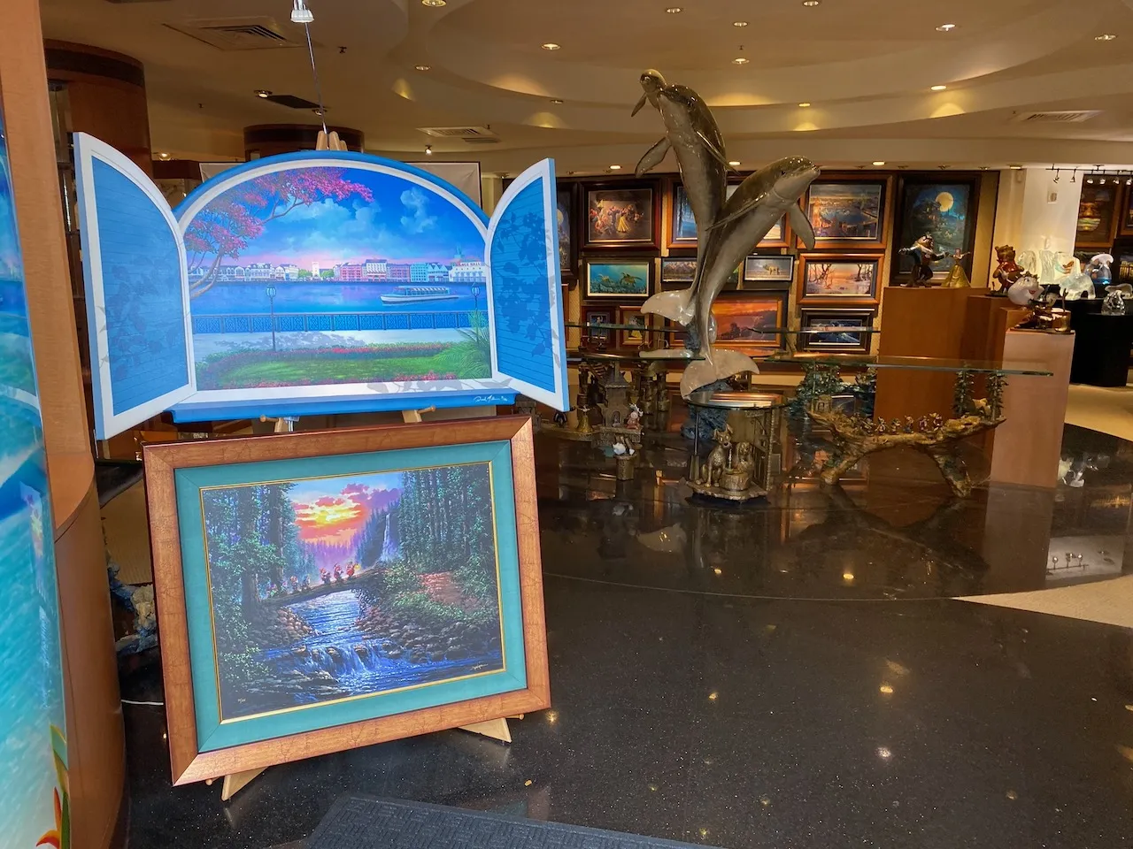 Inside a Promenade gallery: framed paintings, a bronze dolphin sculpture and glass art